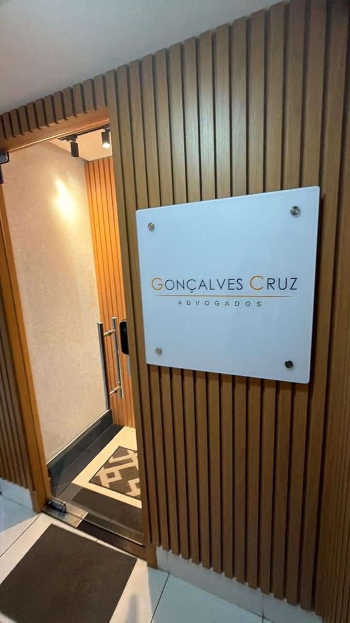 Entrada do escritório Gonçalves Cruz Advogados, com placa na parede de ripas de madeira